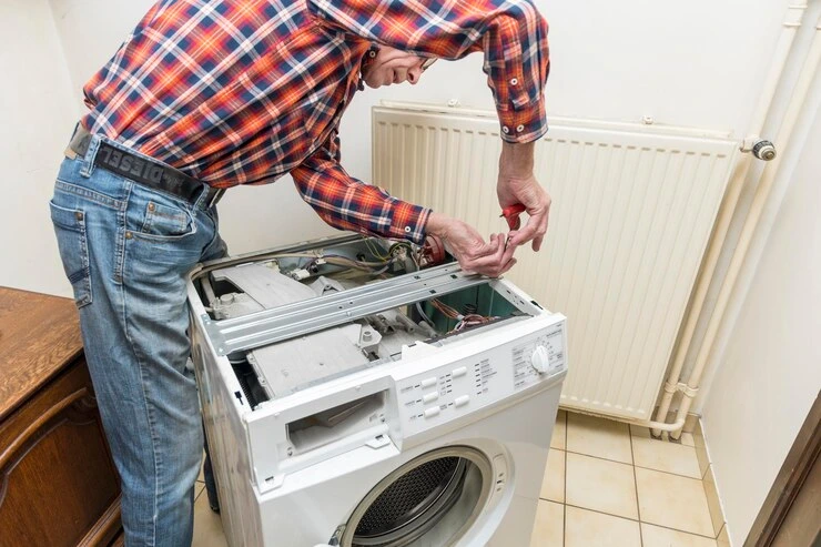 Mann reparerer ødelagt vaskemaskin med verktøy